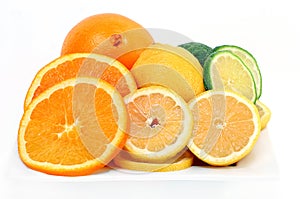 Citrus fruits of oranges, lemons and limes cut and whole on a white plate and background