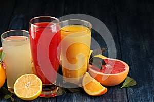 Citrus juices. Orange, grapefruit and lemon juice with fresh fruits on a blue wooden table. space for text