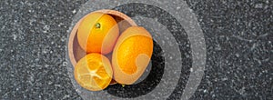 Citrus kumquat fruits on a dark background, organic food market. Long banner format. top view