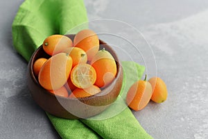 Citrus kumquat fruits in wooden bowl on linen cloth background. Healthy vegan food