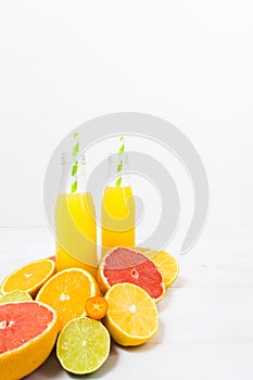 Citrus lemonade in the bottles with ingredients on the white woo