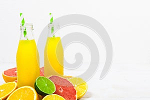 Citrus lemonade in the bottles with ingredients on the white woo