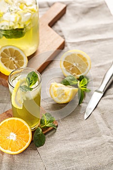 Citrus lemonade with ice cubes in glass Cup on vintage decanter. Summer drink Limoncello