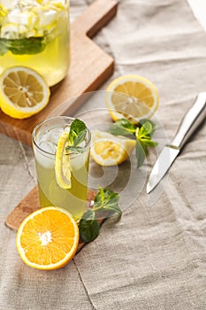 Citrus lemonade with ice cubes in glass Cup on vintage decanter. Summer drink Limoncello