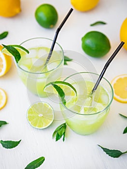 Citrus lemonade with limes, mint and lemons in glass on white table