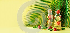 Citrus lemonade - mint, lemon, strawberry and tropical palm leaves on yellow background. Detox drink. Banner with copy photo