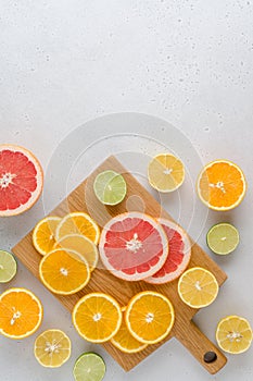 Citrus lobule composition on chopping board. Many halved lemons, limes, grapefruits. Vertical