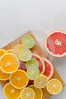 Citrus lobule composition on cutting board. Many halved lemons, limes, grapefruits. Vertical