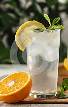 Citrus mint lemonade with ice cubes in glass Cup next to vintage carafe. Summer drink Limoncello