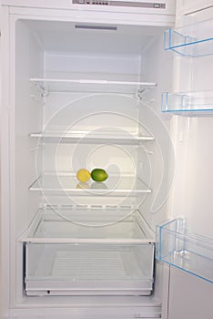 Citrus in open empty refrigerator.