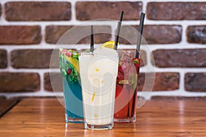 Citrus and raspberry lemonades, PiÃ±a colada on a wooden table in a cafe.