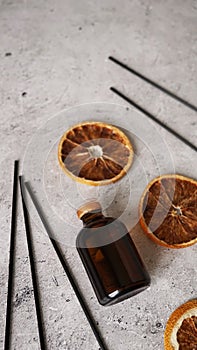 Citrus reed diffuser on dark background. Bottle, sticks and dry oranges