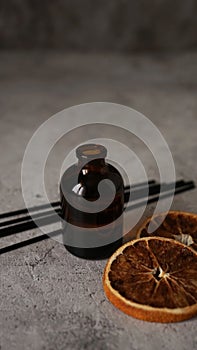 Citrus reed diffuser on dark background. Bottle, sticks and dry oranges