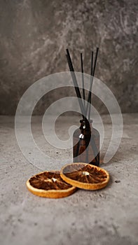 Citrus reed diffuser on dark background. Bottle, sticks and dry oranges