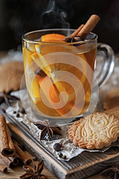 Citrus tea with cinnamon and cardomom in a glass. With sweet homemade almond cookies. Country style. Kraft paper.