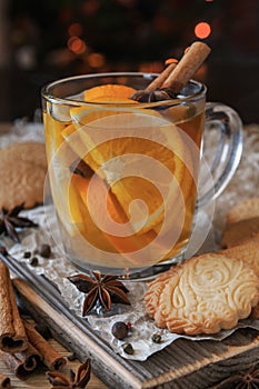 Citrus tea with cinnamon and cardomom in a glass. With sweet homemade almond cookies. Country style. Kraft paper. Wooden