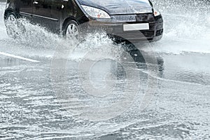 City asphalt road during heavy rain. black car in motion.