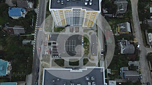 City block. Modern multi-storey buildings among cottages. Flying at dusk at sunset. Aerial photography.