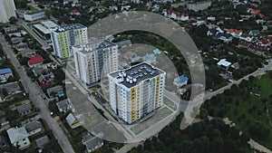 City block. Modern multi-storey buildings among cottages. Flying at dusk at sunset. Aerial photography.