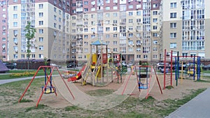 In the city block, among the residential buildings there is a children's playground with slides, swings and a sandbox. Lawns and p