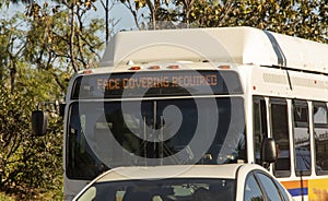 City bus in traffic with electronic sign requiring face masks due to covid-19