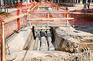 City district heating pipeline reparation and reconstruction parallel with the street with orange construction safety net or barri