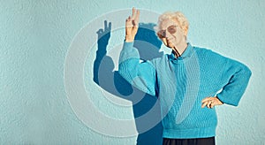 City, fashion and senior woman with peace sign on blue background wall enjoy freedom, weekend and retirement. Energy
