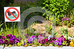 city flower bed with a sign forbidding trampling on flowers