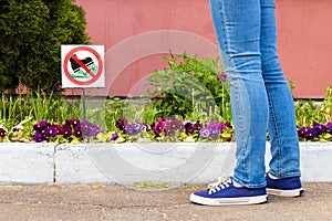 city flower bed with a sign forbidding trampling on flowers.