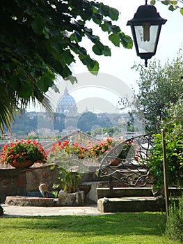 City garden with the view of the dome of the Basilic of St. Peter to Rome in Italy.