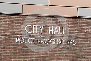 City Hall and Police Headquarters in bold stainless steel text on brick. City Hall is the administration building of a municipal