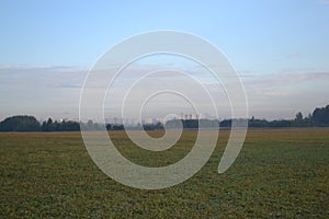 City is on the horizon. Early morning the field and the sky with clouds.