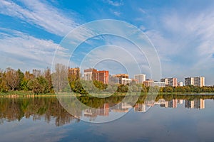 City landscape. Moscow. Residential area Izmailovo and its reflection in the pond in early autumn. View from Izmailovsky Island