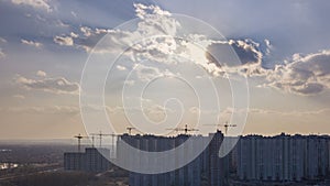 City landscape with new houses under construction on a background of cloudy sky with sunnlight. Aerial view of the drone