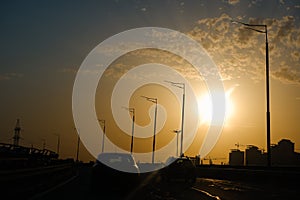 City landscape in the rays of the setting sun. Highways, cars, high-rise buildings and cranes in the light. Urban landscape