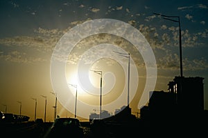 City landscape in the rays of the setting sun. Highways, cars, high-rise buildings and cranes in the light. Urban landscape