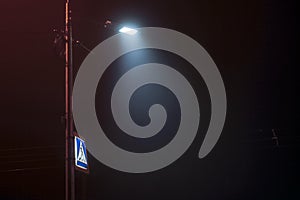 city lights at night above the pedestrian crossing sign in fog