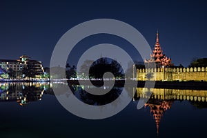 City and Mandalay Palace`s lit wall at dusk