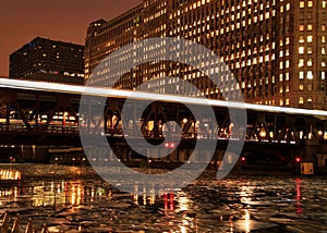 City night lights are illuminated from Chicago bridge and moving el train speeding across it.