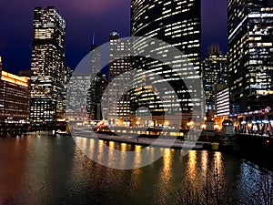 City night lights reflect onto a nearly frozen Chicago River in the loop during winter evening rush hour.