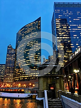 City night lights reflect over freezing Chicago River and el train passing over Lake Street in winter.