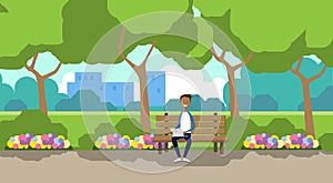 City park african man holding laptop sitting wooden bench green lawn flowers trees cityscape template background