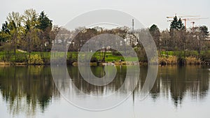 City park with cranes symmetrically reflected in lake water