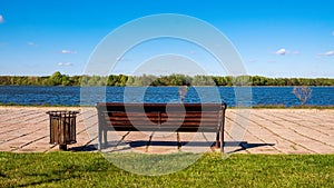 The city park. An empty bench overlooking the water surface