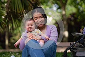 In city park a happy and adorable 5 month old baby girl and her Asian Chinese woman share a playful moment on a blanket amidst the