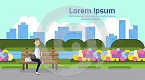 City park man holding laptop sitting wooden bench green lawn flowers trees cityscape template background copy space