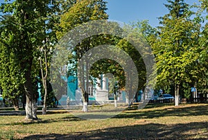 City park on sunny day, unknown woman walking to old building