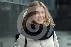 City portrait of young beautiful blonde stylish girl posing in spring fall outdoors in white coat black knitted scarf. Vintage fil