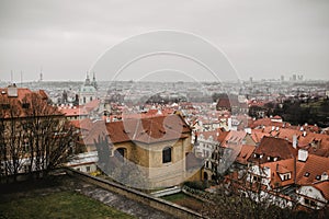 City of Prague with red roofs and Church in fog. City view of Praha old city. Rustic grey colors toning