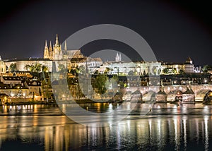 The city of Prague with St. Vitus Cathedral on the hill, Charles Bridge and the Vltava river at night